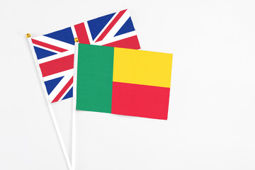 Benin and United Kingdom stick flags on white background. High quality fabric, miniature national flag. Peaceful global concept.White floor for copy space.