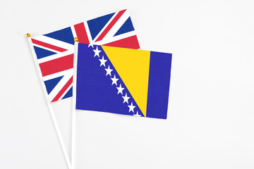 Bosnia Herzegovina and United Kingdom stick flags on white background. High quality fabric, miniature national flag. Peaceful global concept.White floor for copy space.