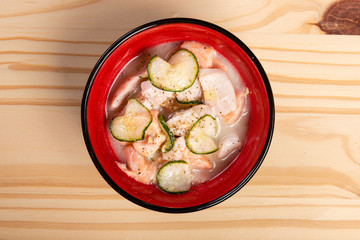Salmon Ceviche with Cucumber and Black Pepper. Symbol of Peruvian Food. Served in a bowl over pine wood background.