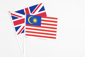 Malaysia and United Kingdom stick flags on white background. High quality fabric, miniature national flag. Peaceful global concept.White floor for copy space.