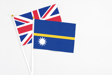 Fototapeta premium Nauru and United Kingdom stick flags on white background. High quality fabric, miniature national flag. Peaceful global concept.White floor for copy space.