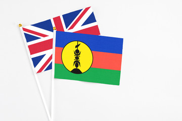New Caledonia and United Kingdom stick flags on white background. High quality fabric, miniature national flag. Peaceful global concept.White floor for copy space.