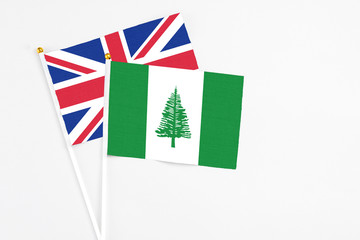 Norfolk Island and United Kingdom stick flags on white background. High quality fabric, miniature national flag. Peaceful global concept.White floor for copy space.