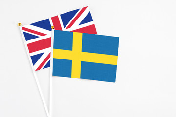 Obraz premium Sweden and United Kingdom stick flags on white background. High quality fabric, miniature national flag. Peaceful global concept.White floor for copy space.