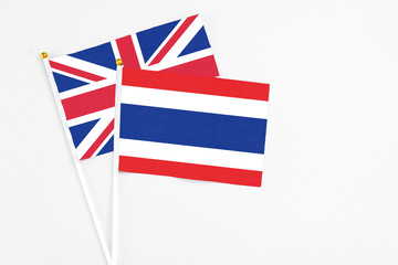 Fototapeta premium Thailand and United Kingdom stick flags on white background. High quality fabric, miniature national flag. Peaceful global concept.White floor for copy space.