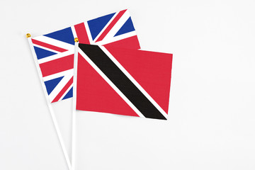 Trinidad And Tobago and United Kingdom stick flags on white background. High quality fabric, miniature national flag. Peaceful global concept.White floor for copy space.