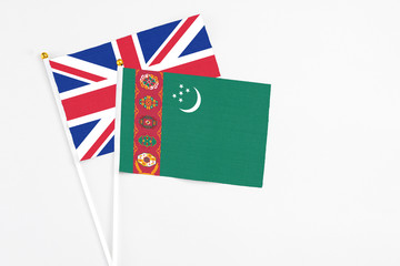 Turkmenistan and United Kingdom stick flags on white background. High quality fabric, miniature national flag. Peaceful global concept.White floor for copy space.