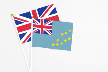 Fototapeta premium Tuvalu and United Kingdom stick flags on white background. High quality fabric, miniature national flag. Peaceful global concept.White floor for copy space.