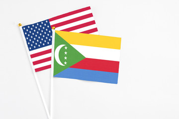 Comoros and United States stick flags on white background. High quality fabric, miniature national flag. Peaceful global concept.White floor for copy space.