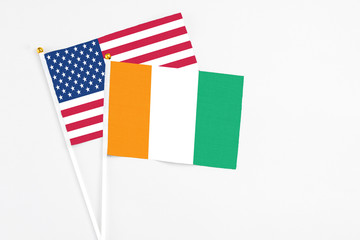 Fototapeta na wymiar Cote D'Ivoire and United States stick flags on white background. High quality fabric, miniature national flag. Peaceful global concept.White floor for copy space.