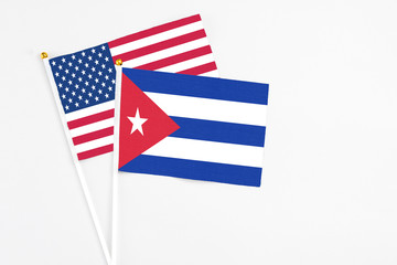 Cuba and United States stick flags on white background. High quality fabric, miniature national flag. Peaceful global concept.White floor for copy space.