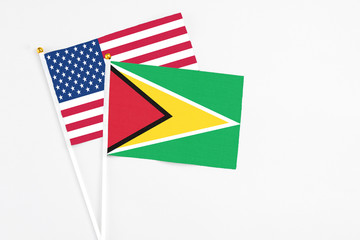 Guyana and United States stick flags on white background. High quality fabric, miniature national flag. Peaceful global concept.White floor for copy space.