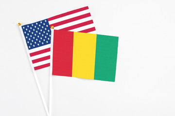 Fototapeta na wymiar Guinea and United States stick flags on white background. High quality fabric, miniature national flag. Peaceful global concept.White floor for copy space.