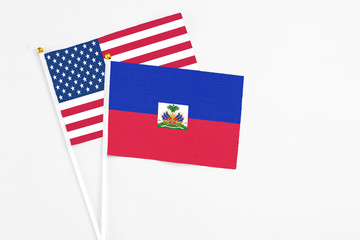 Haiti and United States stick flags on white background. High quality fabric, miniature national flag. Peaceful global concept.White floor for copy space.
