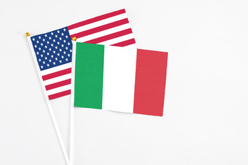 Fototapeta na wymiar Italy and United States stick flags on white background. High quality fabric, miniature national flag. Peaceful global concept.White floor for copy space.