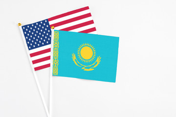 Kazakhstan and United States stick flags on white background. High quality fabric, miniature national flag. Peaceful global concept.White floor for copy space.