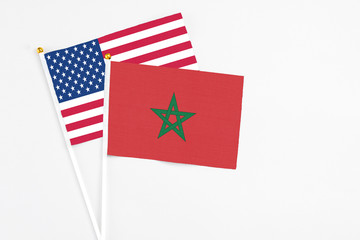 Morocco and United States stick flags on white background. High quality fabric, miniature national flag. Peaceful global concept.White floor for copy space.