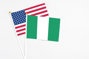 Nigeria and United States stick flags on white background. High quality fabric, miniature national flag. Peaceful global concept.White floor for copy space.