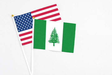 Norfolk Island and United States stick flags on white background. High quality fabric, miniature national flag. Peaceful global concept.White floor for copy space.
