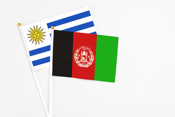 Afghanistan and Uruguay stick flags on white background. High quality fabric, miniature national...