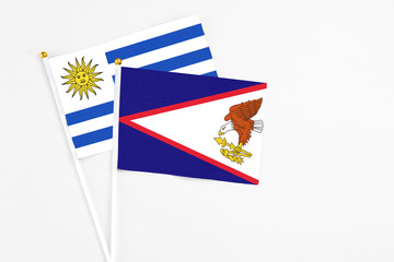 American Samoa and Uruguay stick flags on white background. High quality fabric, miniature national...