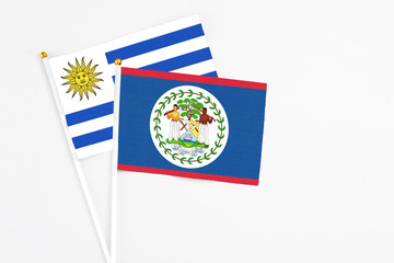 Belize and Uruguay stick flags on white background. High quality fabric, miniature national flag. Peaceful global concept.White floor for copy space.