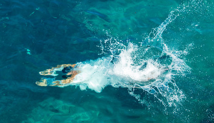 A man swims in the blue water of the sea