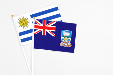 Falkland Islands and Uruguay stick flags on white background. High quality fabric, miniature national flag. Peaceful global concept.White floor for copy space.