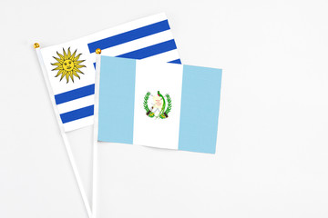 Guatemala and Uruguay stick flags on white background. High quality fabric, miniature national flag. Peaceful global concept.White floor for copy space.