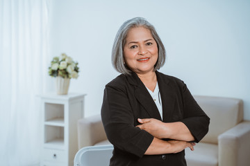 Confident senior business woman standing with crossed hands