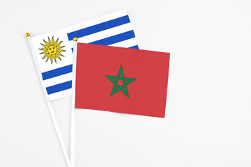 Morocco and Uruguay stick flags on white background. High quality fabric, miniature national flag. Peaceful global concept.White floor for copy space.