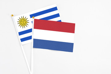 Netherlands and Uruguay stick flags on white background. High quality fabric, miniature national flag. Peaceful global concept.White floor for copy space.