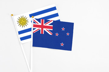 Fototapeta premium New Zealand and Uruguay stick flags on white background. High quality fabric, miniature national flag. Peaceful global concept.White floor for copy space.