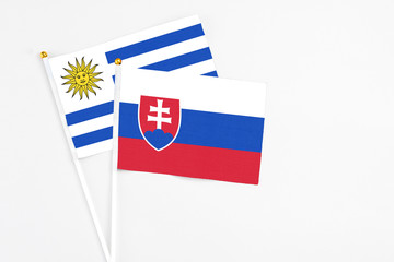 Slovakia and Uruguay stick flags on white background. High quality fabric, miniature national flag. Peaceful global concept.White floor for copy space.