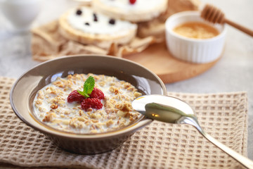 Baked granola with milk and raspberries in a plate, whole grain breads and freshly squeezed juice. A wholesome and dietary breakfast. Delicious muesli