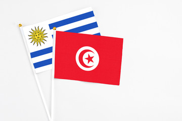 Tunisia and Uruguay stick flags on white background. High quality fabric, miniature national flag. Peaceful global concept.White floor for copy space.