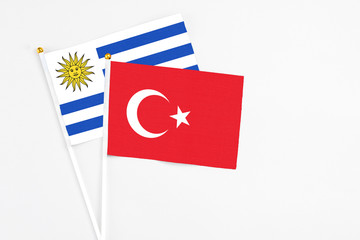 Turkey and Uruguay stick flags on white background. High quality fabric, miniature national flag. Peaceful global concept.White floor for copy space.