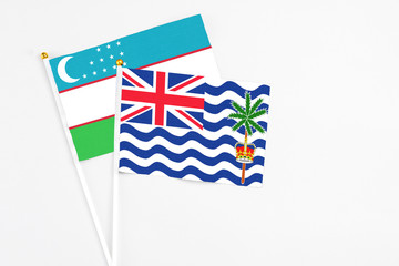 British Indian Ocean Territory and Uzbekistan stick flags on white background. High quality fabric, miniature national flag. Peaceful global concept.White floor for copy space.