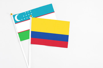 Colombia and Uzbekistan stick flags on white background. High quality fabric, miniature national flag. Peaceful global concept.White floor for copy space.