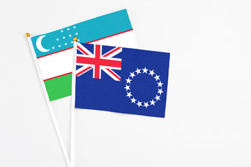 Cook Islands and Uzbekistan stick flags on white background. High quality fabric, miniature national flag. Peaceful global concept.White floor for copy space.