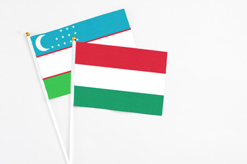 Hungary and Uzbekistan stick flags on white background. High quality fabric, miniature national flag. Peaceful global concept.White floor for copy space.
