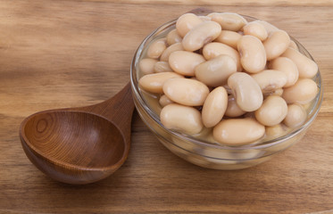 Baked white beans in glass bowl with wooden spoon