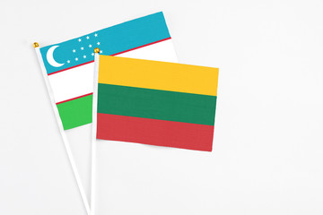 Lithuania and Uzbekistan stick flags on white background. High quality fabric, miniature national flag. Peaceful global concept.White floor for copy space.