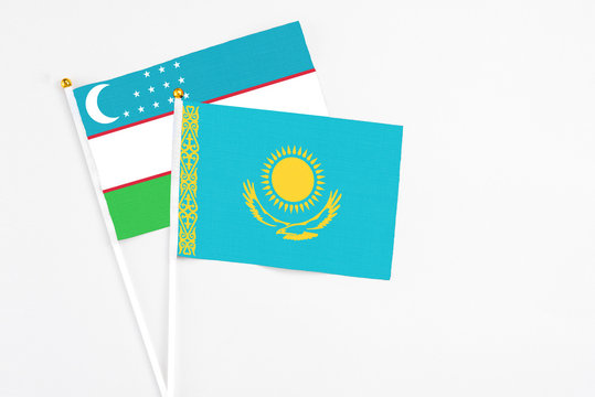 Kazakhstan and Uzbekistan stick flags on white background. High quality fabric, miniature national flag. Peaceful global concept.White floor for copy space.