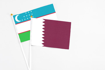 Qatar and Uzbekistan stick flags on white background. High quality fabric, miniature national flag. Peaceful global concept.White floor for copy space.