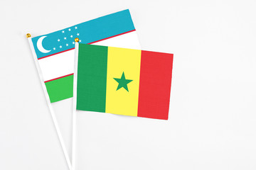 Senegal and Uzbekistan stick flags on white background. High quality fabric, miniature national flag. Peaceful global concept.White floor for copy space.
