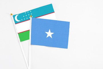 Somalia and Uzbekistan stick flags on white background. High quality fabric, miniature national flag. Peaceful global concept.White floor for copy space.