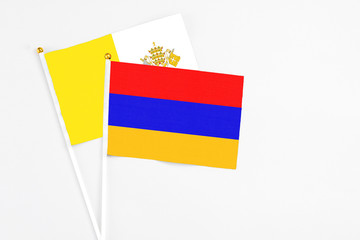 Armenia and Vatican City stick flags on white background. High quality fabric, miniature national flag. Peaceful global concept.White floor for copy space.