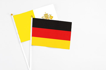 Germany and Vatican City stick flags on white background. High quality fabric, miniature national flag. Peaceful global concept.White floor for copy space.