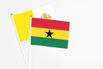 Ghana and Vatican City stick flags on white background. High quality fabric, miniature national flag. Peaceful global concept.White floor for copy space.